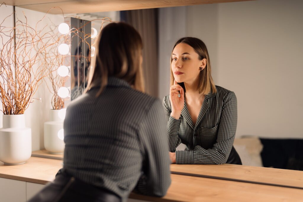 Woman looking in the mirror reflecting on body confidence and low libido