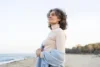 Confident woman in midlife smiling, outdoors or in bright natural light, suggesting wellness and vitality going through Hormone replacement therapy