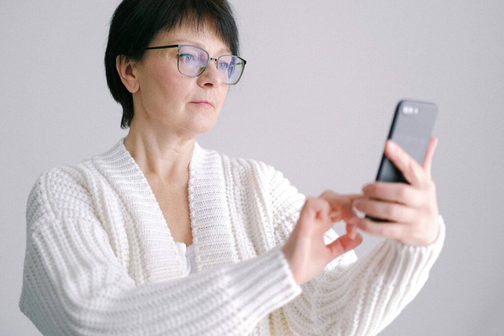 A senior woman holding phone in hand, suffering from back pain menopause