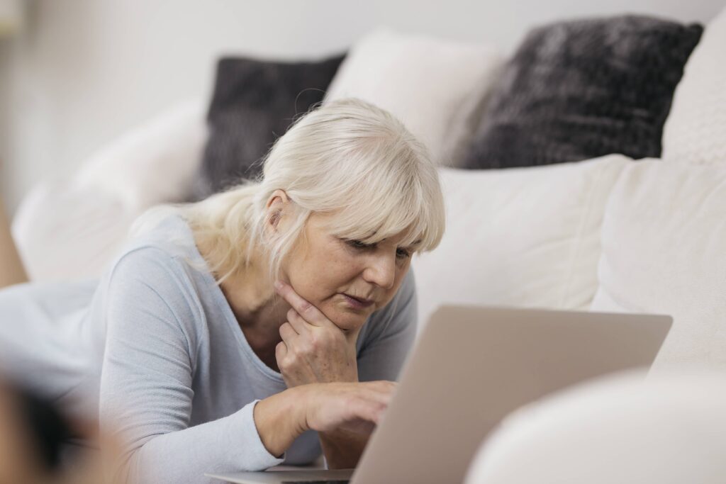 A senior woman in front of her laptop experiencing back pain menopause