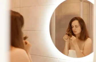 Woman examining hairbrush in mirror - hair loss after menopause