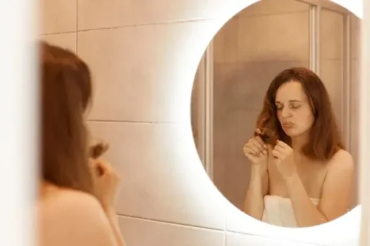 Woman examining hairbrush in mirror - hair loss after menopause